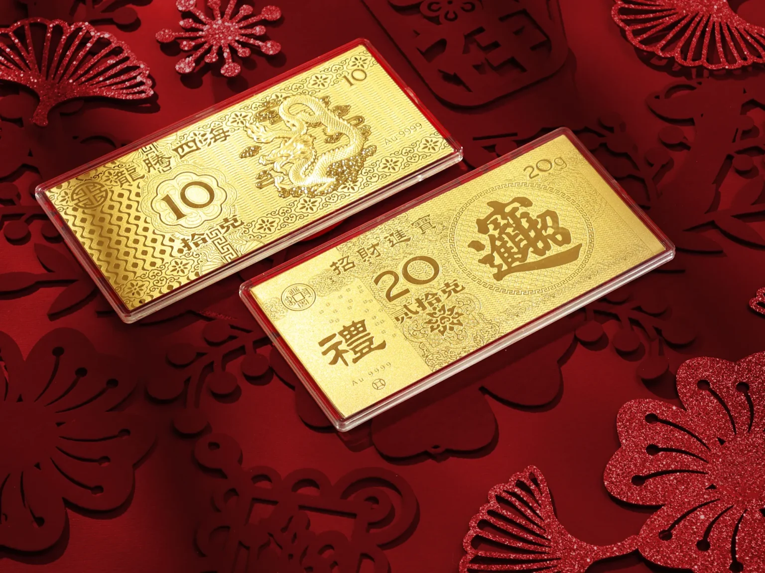 Two 24K gold investment bars with dragon and prosperity engravings on a festive red Lunar New Year background