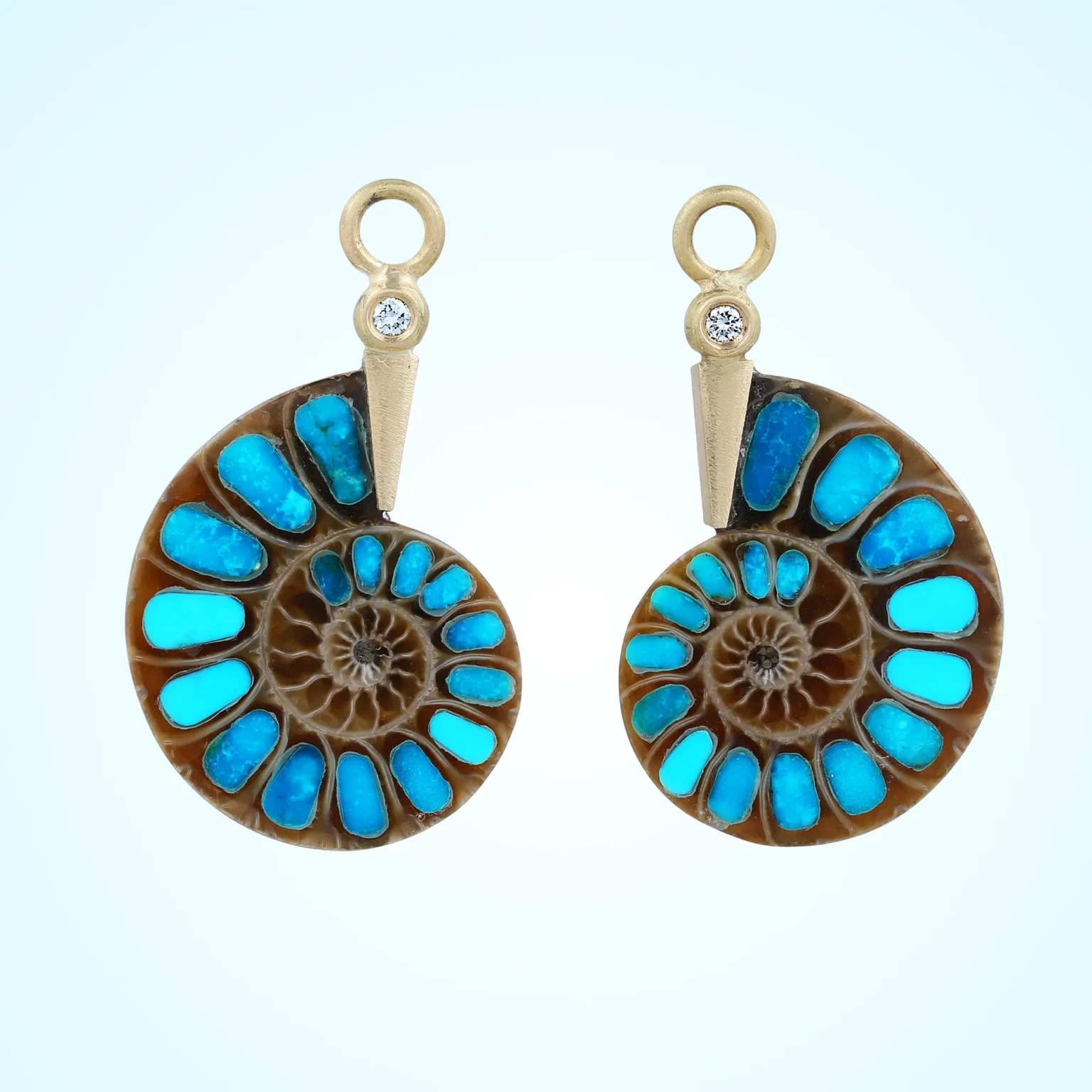 Turquoise inlaid ammonite fossil earrings with gold setting and diamond accents on clean background.