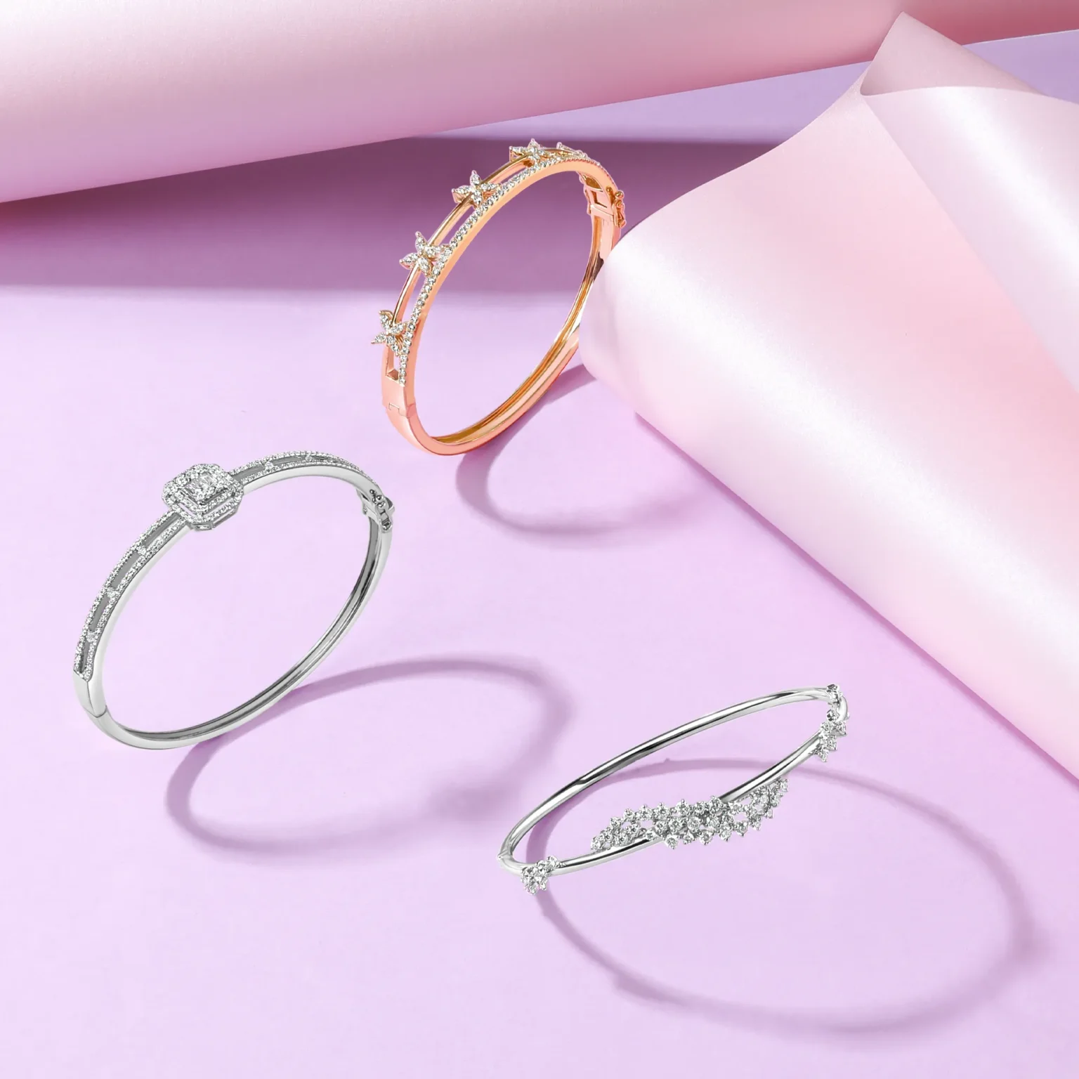 Diamond bangles in white and rose gold styled on soft pink background with modern composition.