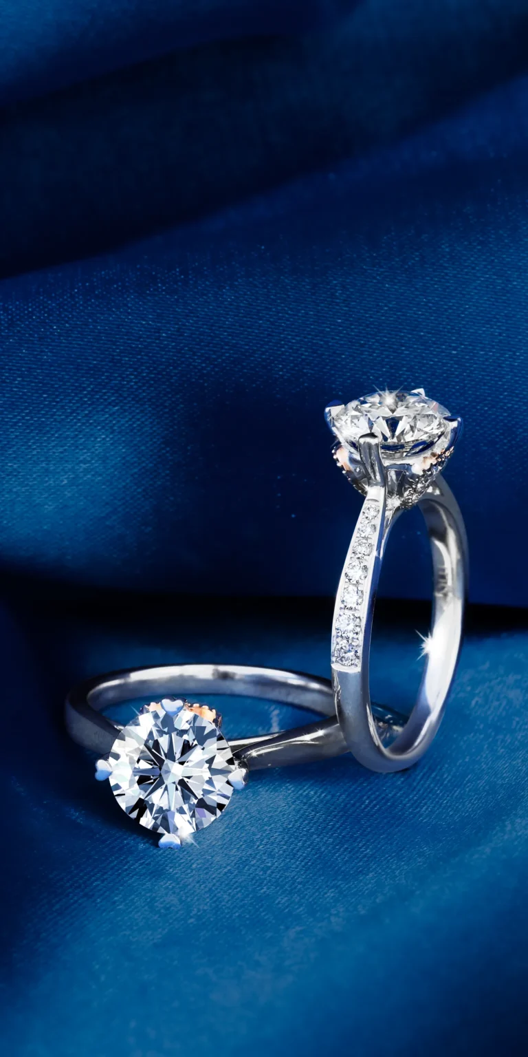 Diamond engagement rings on blue fabric background with high sparkle and contrast.