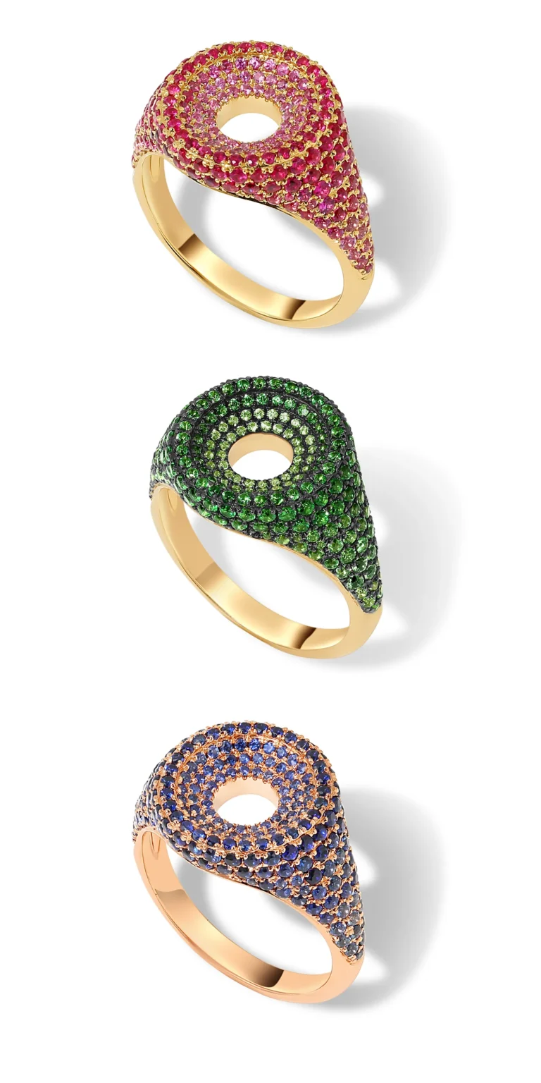 Gold rings with pink, green and blue pav&eacute; gemstones on clean background.