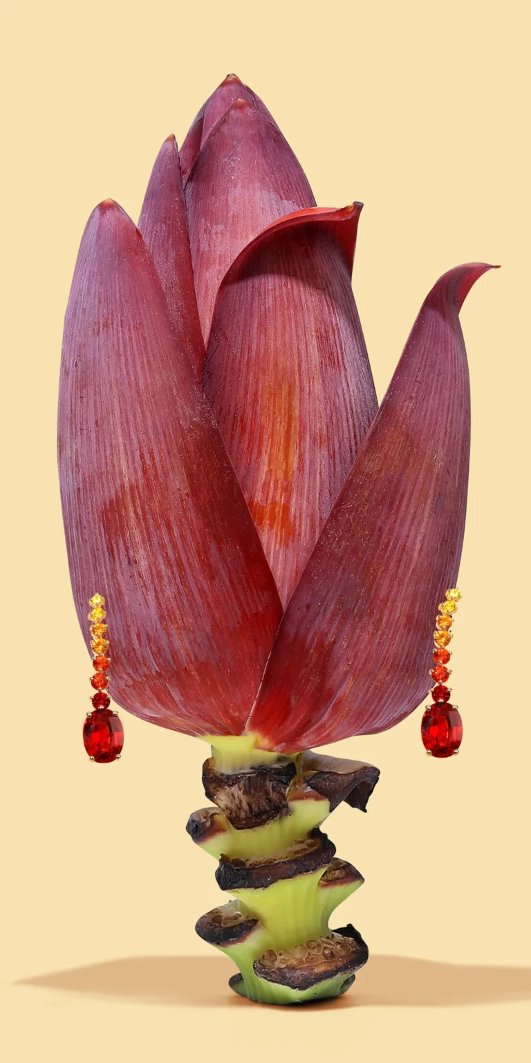 Red gemstone earrings styled with bold floral element on clean background.