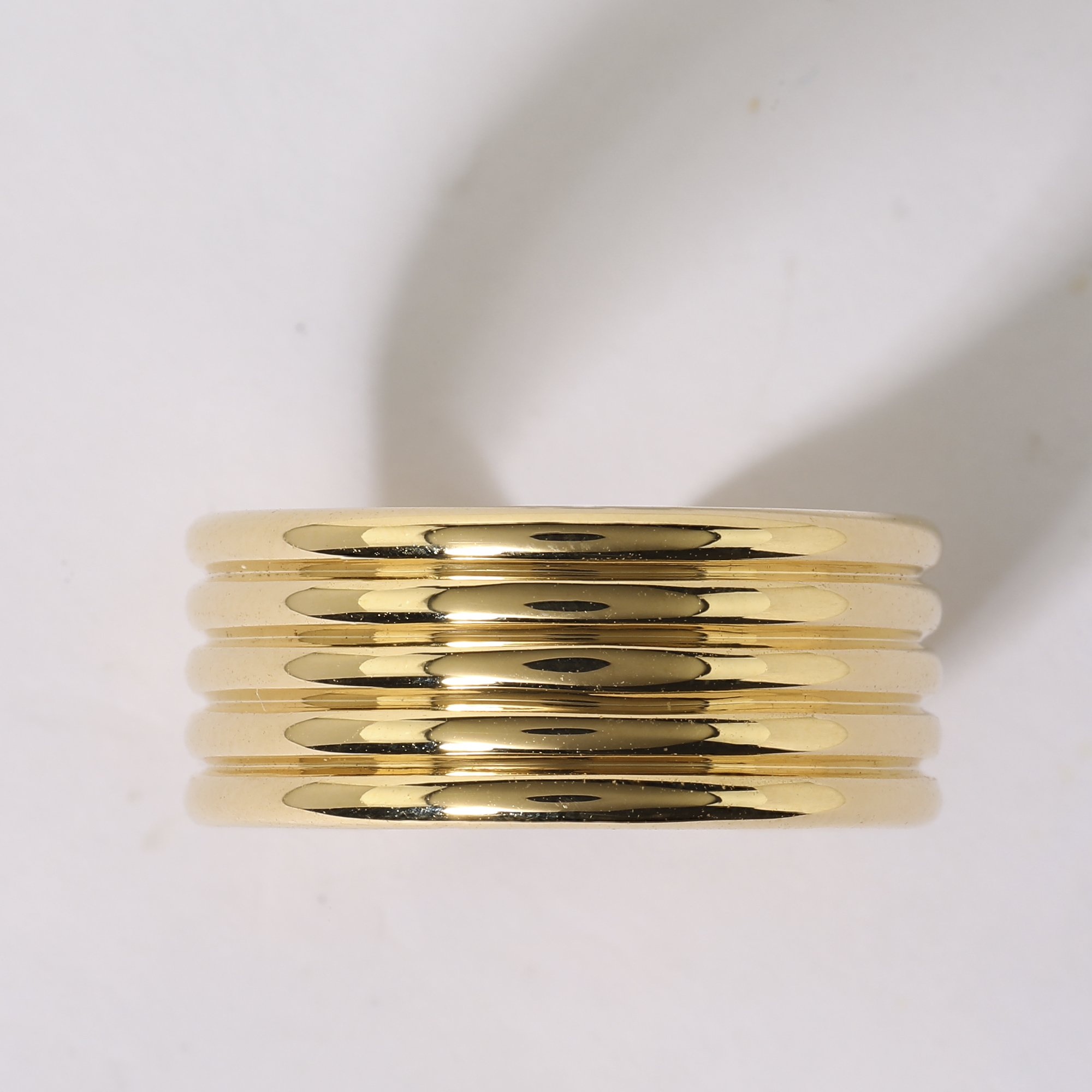Raw jewellery product image of gold ring stack before retouching with uneven lighting and reflections Productpixels Singapore