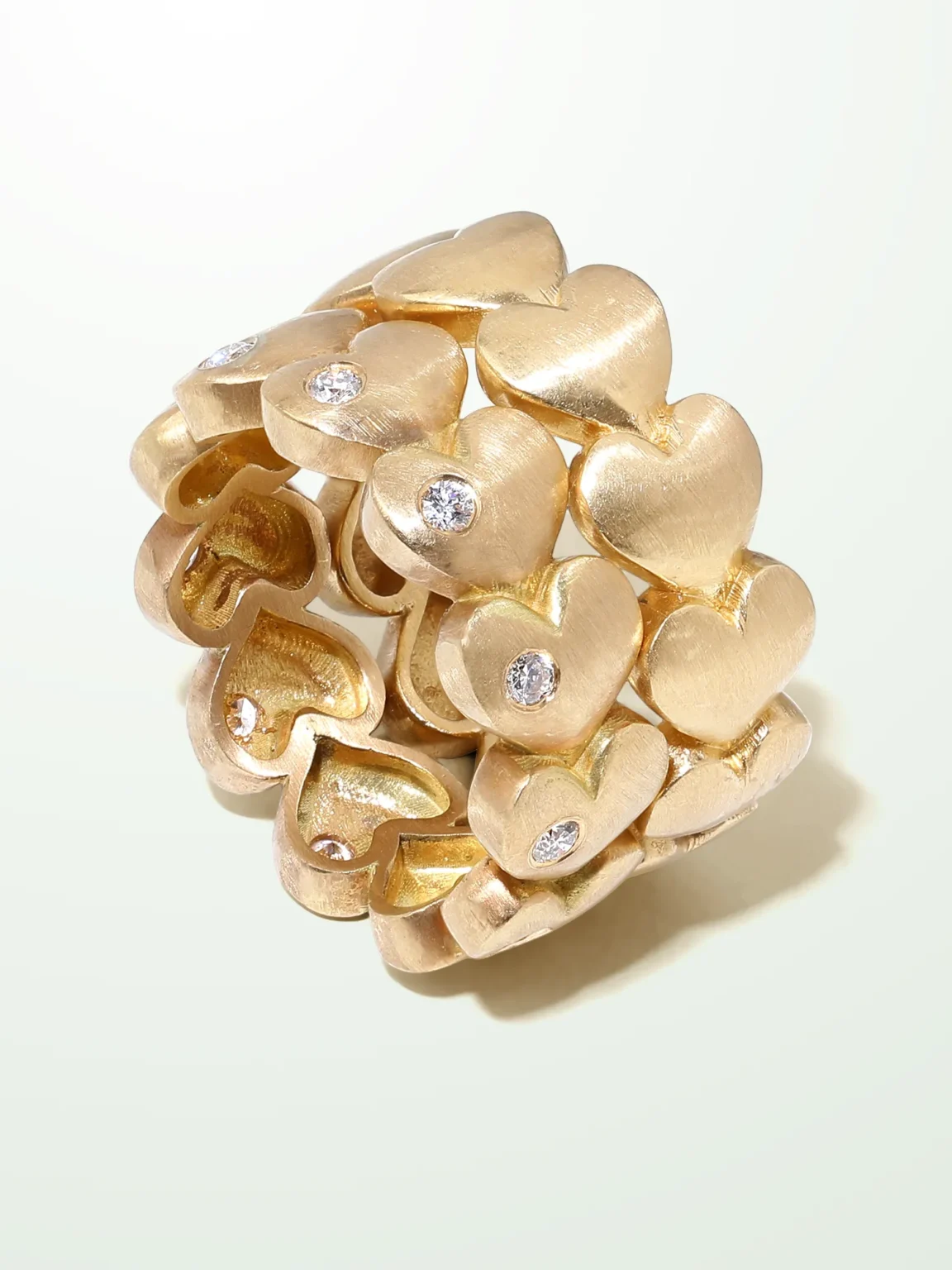 A wide 18K yellow gold statement ring featuring a repeating pattern of sculpted heart motifs with a brushed "velvet" finish and scattered flush-set brilliant diamonds.