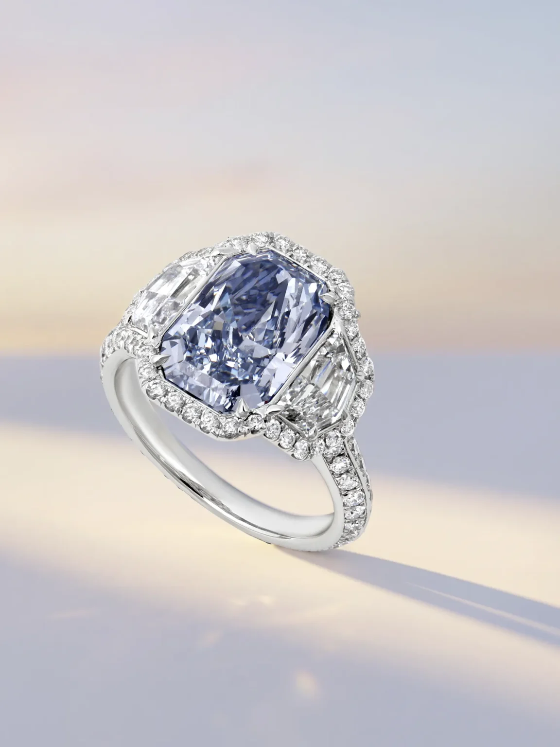 Luxury blue diamond ring photography featuring radiant cut centre stone with halo and side diamonds in white gold, by ProductPixels Singapore